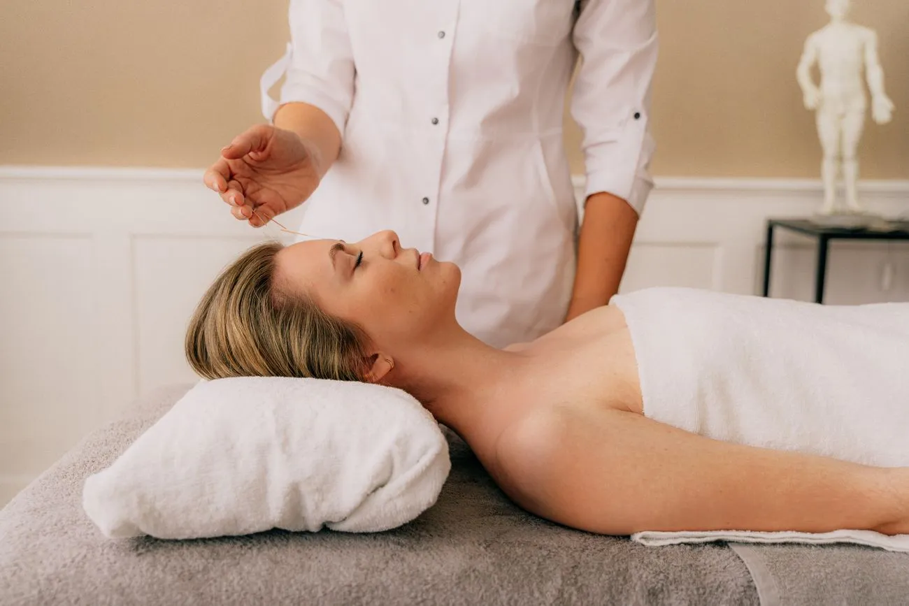 A patient resting calmly on a treatment table during an acupuncture session in a serene clinic room